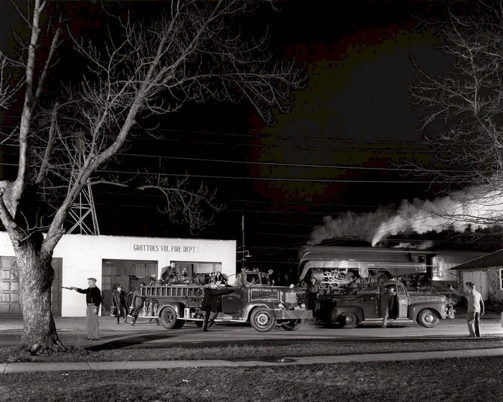THE GROTTOES VOLUNTEER FIRE DEPARTMENT ANSWERS THE CALL AS TRAIN NO. 2 PASSES IN THE BACKGROUND Grottoes, Virginia, 1957 © O. Winston Link / O. Winston Link Museum, Roanoke, Virginia